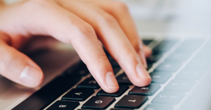 Hands removing a laptop keyboard, showing how to open a laptop keyboard safely to access underlying components like cables and screws.