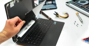 Hands detaching a laptop screen, showing how to open a laptop screen safely for repair or replacement, as explained by Electro Gadget Plus.